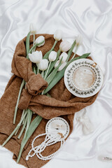 Flat lay brown knitted sweater, coffee and bouquet of fresh tulips.  Sunday relaxing, vintage mood and lifestyle concept. Cozy spring composition.