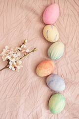 Beautiful watercolor paints on Easter eggs that lie on a delicate pink fabric along with a blossoming branch. Easter concept.
