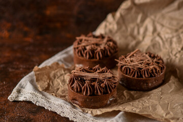 sand tartlets decorated with chocolate cream lie on craft paper on a brown background. sweet desserts for a holiday party. homemade baking