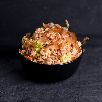 hot second courses of Japanese cuisine. Chahan rice with shrimp and vegetables in a black bowl on a dark background