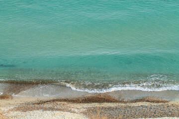 View of the sand, pebbles and clear sea from above. Marine background.