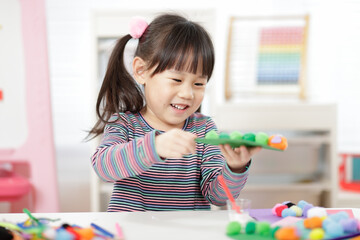 young girl hand makes caterpillar craft for home schooling