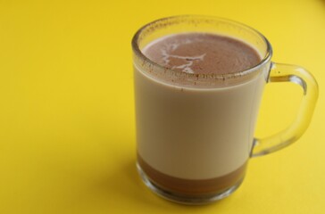 a cup of hot chocolate cocoa on a bright yellow background with room for a copyspace text