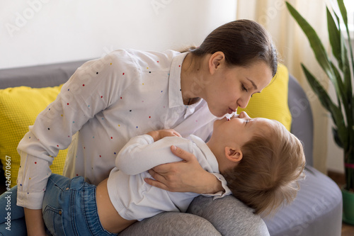 caucasian family little preschool baby boy and mom young woman hug joyfully together in living room at home with happiness smile. Child son congratulates on Mother's Day. Motherhood, childhood concept