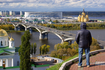 Man admires the panorama of Nizhny Novgorod. View of the new stadium and the Kanavinsky bridge. Focus on the man. - 424072051