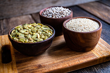 Peeled pumpkin, sunflower and sesame seeds in a wooden bowl on a wooden table. Bakery ingredients. Products for tasty and healthy food.