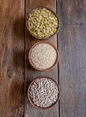Peeled pumpkin, sunflower and sesame seeds in a wooden bowl on a wooden table. Bakery ingredients. Products for tasty and healthy food.