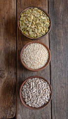 Peeled pumpkin, sunflower and sesame seeds in a wooden bowl on a wooden table. Bakery ingredients. Products for tasty and healthy food.