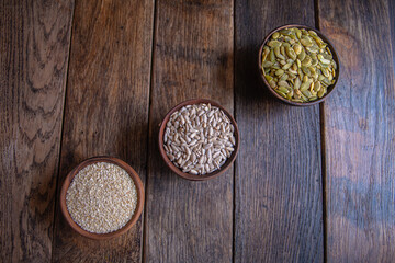 Peeled pumpkin, sunflower and sesame seeds in a wooden bowl on a wooden table. Bakery ingredients. Products for tasty and healthy food.