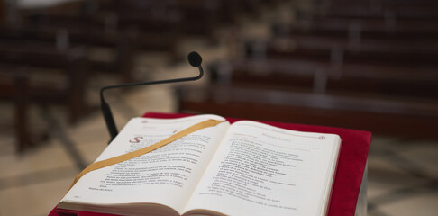 marble lectern with a red felt and a bible with some pews in the