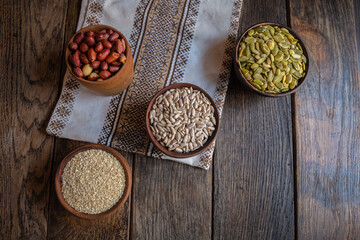Peeled pumpkin, sunflower, nut, and sesame seeds in a wooden bowl on a wooden table. Bakery ingredients. Products for tasty and healthy food.