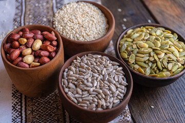 Peeled pumpkin, sunflower, nut, and sesame seeds in a wooden bowl on a wooden table. Bakery ingredients. Products for tasty and healthy food.