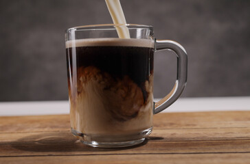 Pour milk into a freshly brewed cup of coffee - studio photography