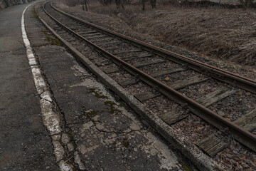 Obraz premium Old, dilapidated and abandoned railway station with rusty railway tracks and wooden railway sleepers