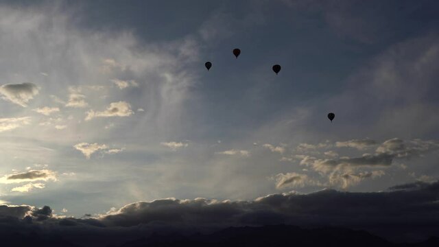 Balloons fly across the sky. A silhouette. Over the mountains. Sunrise. Clouds over the mountains. The general plan. Lots of little balls