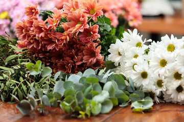 A bouquet of white and red chrysanthemums lies on a wooden table.