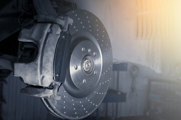 Installation of new perforated brake discs and pads on a modern auto in a car workshop. Blur effect.