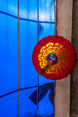 Tongli, China - May 2, 2010: Fish-eye vertical shot into red-golden lantern hanging from blue canvas sunlighted awning.