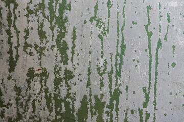 Peeling paint on the wall. Old concrete wall with cracked flaking paint. Weathered rough painted surface with patterns of cracks and peeling. Grunge texture for background and design. High resolution.