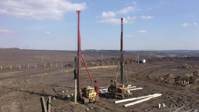 Excavation at a construction site, diesel pile driving machine with rumble and smoke drives piles deep into the ground to ensure the strength of the foundation of the future structure