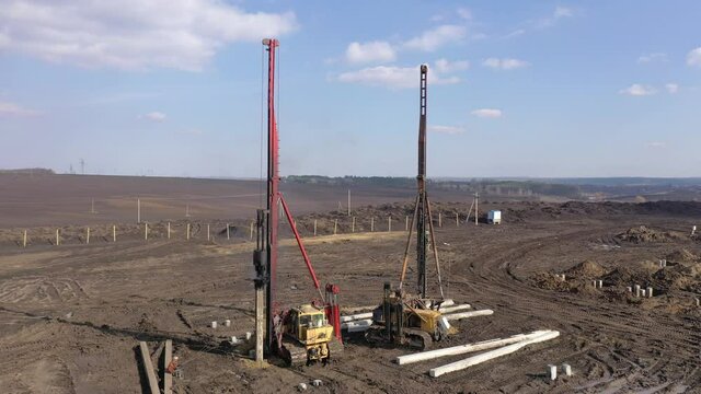 Excavation at a construction site, diesel pile driving machine with rumble and smoke drives piles deep into the ground to ensure the strength of the foundation of the future structure