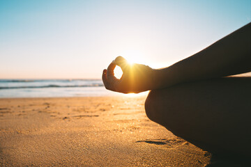 Meditating on the beach at sunrise in the morning. Sitting on the sand in easy pose or sukhasana...
