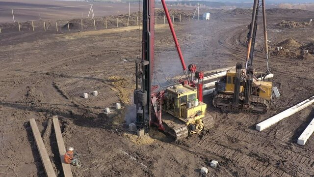 Excavation at a construction site, diesel pile driving machine with rumble and smoke drives piles deep into the ground to ensure the strength of the foundation of the future structure