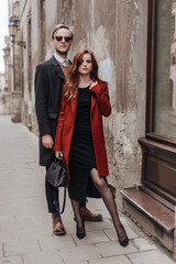 Woman in black dress and wine color coat, man in classic business suit with sweater