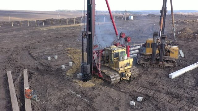 Excavation at a construction site, diesel pile driving machine with rumble and smoke drives piles deep into the ground to ensure the strength of the foundation of the future structure