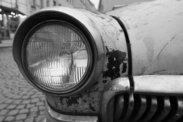 close wide low angle view of an old soviet vintage muscle car headlight with shiny chrome and...