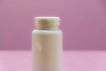 Milky white plastic bottle for storing medicine on pink background