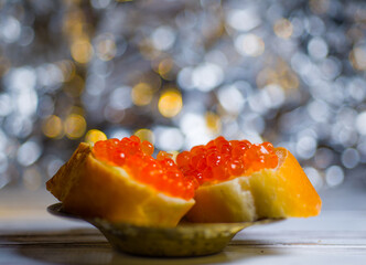 baguettes with red caviar very close close-up on a wooden tray with herbs and a light bright...