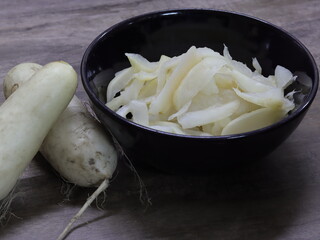 Radishes are flaked and pickled with salt. For cooking, housed in a black ceramic cup.