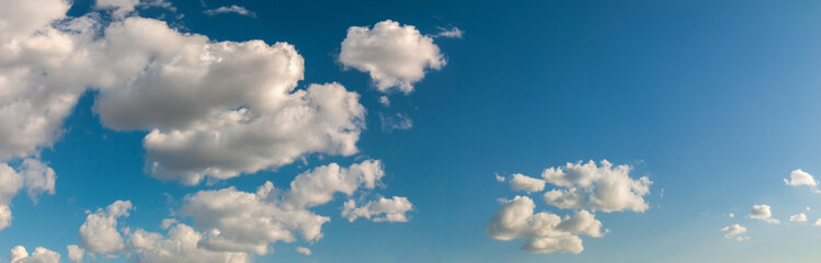 Deep blue sky panorama with rare clouds lit with sunlight