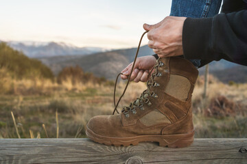 Close-up of a mountaineer tying the laces of brown boots