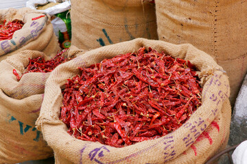 fresh whole dry red chilies stored in bag for sell in a market stall