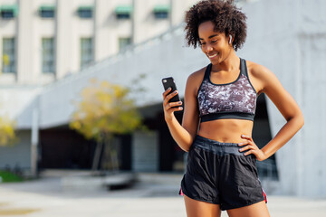 Athletic woman using her mobile phone outdoors.