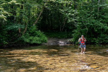 Fototapeta premium Woman Wades Through Wide Creek