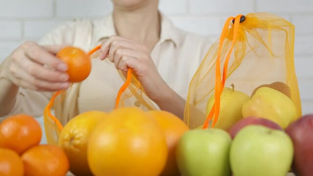 Woman with an eco shopper. Woman puts fruits in reusable eco bags.