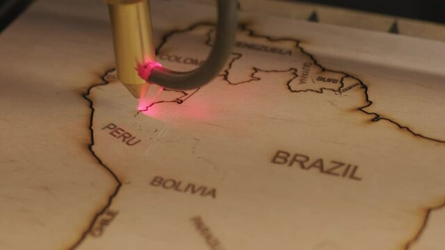 Cnc laser cutting machine cuts world map on wooden plank and plywood