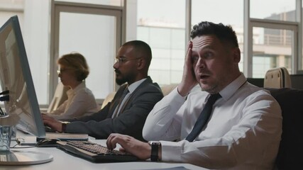 Medium slow motion footage of three multi-ethnic information security specialists in formalwear working on computers fighting against hacker attack