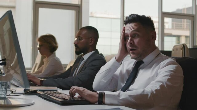 Medium slow motion footage of three multi-ethnic information security specialists in formalwear working on computers fighting against hacker attack
