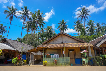 Fototapeta na wymiar Traditional house of beachside village with coconut trees under blue skies. Daylight in the Countryside of Asia. 