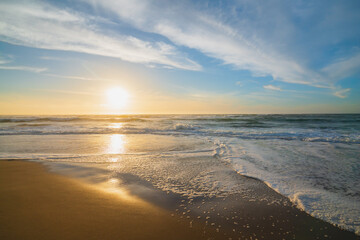 Sunset on the beach. Beautiful tranquil scene of empty sand beach, turquoise colored water, and cloudy sky
