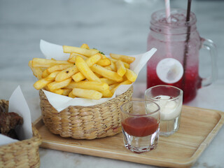 French fries, Potato chips Yellow crispy fries in wooden basket, snack delicious and Red lemon soda water flavoured drink, Cool Drinks Beverages with ice in clear glass on white table