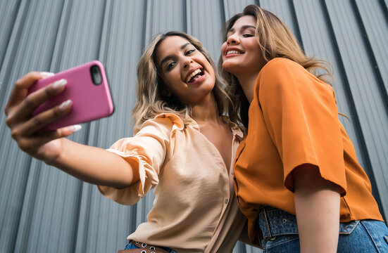 Two Friends Taking Selfie With Phone Outdoors.