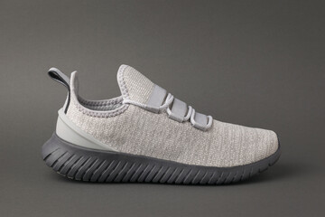 Stylish grey running shoe on a dark grey background.