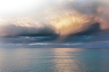 Fototapeta premium Beautiful clouds over sea. Sunlight through clouds. Beach with trees on horizon. Summer landscape. Travel background.