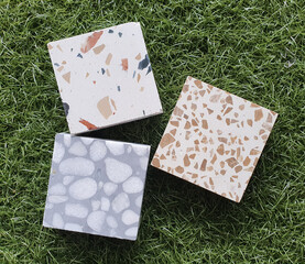 terrazzo stone samples in multi pattern of stone pigments texture placed on natural green arificial grass. set of different marble surface material for flooring in architecture works.