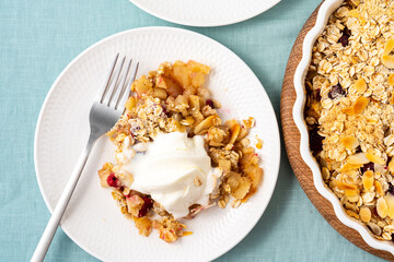 Close up apple pear crumble with ice cream, streusel. Healthy diet dessert stewed fruit topped crisp oats crumbly mixture with nuts. Apple cobbler gluten free pie in plate on tablecloth. Top view